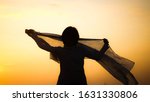 Small photo of Blurred shadow of the woman / girl raise scarf up and sunlight shining in the morning ( sunrise ) with golden / yellow sky background