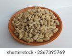 Groundnut, Goober or Monkey Nut, or Arachis hypogaea, on a wooden plate, isolated in white background. Ready to eat as snack