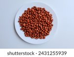 Fried groundnut, Goober or Monkey Nut, or Arachis hypogaea. On a white plate, isolated on white background. Flat lay or top view