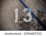 Prime number 13. Fibonacci number thirteen on concrete. Chalk. Date Friday 13th. No luck. Superstition. Ominous sign. Unlucky. Dire. Mathematical unit. Cursed. Cell count. Background. Digit. Outside.