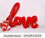 A red foil balloon in the form of the word Love  on white background. balloon letters, concept of romance, Valentine's Day, Mothers Womans Day. Love word balloons