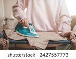 Small photo of clothes, appliance, home, housework, iron, ironing, laundry, steam, clean, domestic. close-up young woman's hand using electric steam, water vapor from iron press pile shirt clothes on an ironing.