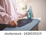 Small photo of clothes, appliance, home, housework, iron, ironing, laundry, steam, clean, domestic. close-up of ironing clothes on an ironing board after then young women is going to folding clothes on that.