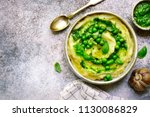 Mashed potato with pesto sauce and sweet pea in a bowl over light slate, stone or concrete background.Top view with copy space.