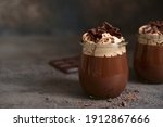 Delicious chocolate mousse or pudding with whipped cream in a vintage glass jar on a dark slate, stone or concrete background.