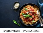 Small photo of Spaghetti with meat balls in tomato sauce in a black bowl on a dark slate, stone or concrete background. Top view with copy space.