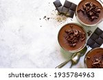 Homemade delicious chocolate mousse or panna cotta  in a glasses on a light slate, stone or concrete background. Top view with copy space.