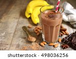 Homemade chocolate banana smoothie in a glass on a rustic wooden background.