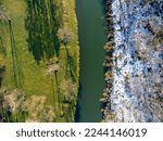 Aerial view. The river as seen from above. Winter, spring. Half and half. Landscape, trees, snow, water, shadows.