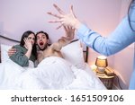 Small photo of Girlfriend is shocker and angry, boyfriend is in the bed with other girl, she threatens to punch him