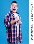 Small photo of Shocked and appalled young teenage boy making a gasp expression, blue background