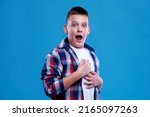 Small photo of Shocked and appalled young teenage boy making a gasp expression, blue background