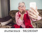 Senior old woman sending love and kisses to her family over skype or viber using her cellphone