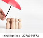 A group of wooden figures with hand holding mini red umbrella.