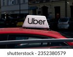 Small photo of KRAKOW, POLAND - AUGUST 12, 2023: Uber logo sign on top of passenger taxi car. Cab transport service, ridesharing company logotype, brand signboard with inscription. Uber transportation smartphone app