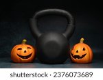 Kettlebell and Halloween pumpkins, spooky Jack-o'-lantern figurine decorations. Healthy fitness lifestyle composition. Gym workout, sport training concept. Staying in shape during autumn fall season.