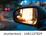 Side mirror on car reflects a city lights 