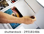 man's hand checking color proofs for printing, during production