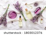 Lavender oils serum and lavender flowers on white fabric. Skincare cosmetics products. Set natural spa beauty products. Lavender essential oil, serum, body butter, massage oil, liquid. Flat lay