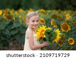 Happy smiling little girl holding big sunflower bouquet. Child playing with sunflowers. Kids picking fresh sun flowers gardening in summer day.