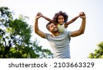Small photo of Portrait of happy black father carrying daughter on back outdoors. Family happiness love concept.