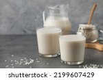 Small photo of Glasses of vegetable rice milk and a jug on a gray background. Vegetarian food, lactose free milk. Copy space