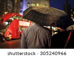 Back view of couple under the umbrella in the evening against the double-decker in London. Image with selective focus