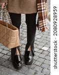 Small photo of female legs in trendy black flared jeans with slits and loafers, caramel bag in hand, details of stylish autumn fashion outlook