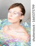 Small photo of Artistic portrait of a beautiful girl with silver make-up Light color With color film dress