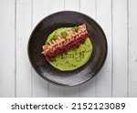 Close-up of savory Japanese salmon tataki dish topped with sesame and served with crispy strips. isolated on modern background. selective focus