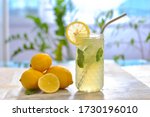 Citrus iced lemonade in pitcher and glasses with lemon slice and mint leaves decoration and on marble table on natural background. Fresh summer drink beautiful picture. Copy space