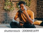 Small photo of Black young man listening to music otr telecoference on mobile phone. Technologies and online social media