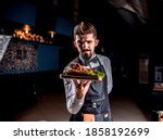 Small photo of Professional flunky helpfully serves cooked dish at a festive event.