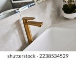 Small photo of Details of modern tapware - a brushed gold flick mixer tap in a bathroom.