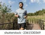 Small photo of Man interval training sports lifestyle. Fast running in the park and fitness exercises for cardio and sportswear T-shirt. Slender figure of a man jogging.