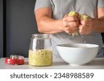 Small photo of Unrecognizable man draining cabbage to prepare homemade sauerkraut or fermented cabbage.