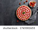 Small photo of Delicious strawberry tart with whipped cream and mascarpone, on a dark concrete background. Top view. Copy space.