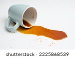 Small photo of Coffee spill from a blue cup on white background, soft focus close up
