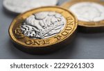 Small photo of British coins lie on gray surface. One pound sterling coin closeup. Economy and money. Bank of England. UK currency and treasury. Pound illustration. Macro