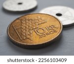 Norwegian coins lie on gray surface. 10 Norges kroner coin close-up. National currency of Norway. News about economy or finance. Bank and loan. Savings and interest. Krone and Norges Bank. Macro