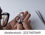 Small photo of A diamond dealer participating in an international jewellery exhibition evaluates the quality and color of diamonds using a magnifying glass.
