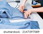 Small photo of A tailor stabs a trouser leg with a needle. Clothes sewing. Clothing repair. Tailoring. Close up view