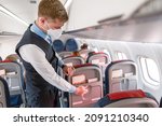 Small photo of Flight attendant in face mask preparing passenger seat in airplane