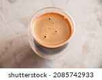 Top view of coffee in glass with double walls on concrete background