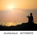 Small photo of Entreat concept: Black and white christian prayer kneeling and praying to God over sunset beach background.