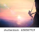 Adventure concept: Silhouette bold heroic man try to climb with rope over natural rocky wall wide valley autumn sunset mountain background
