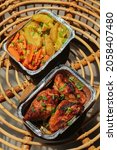 Small photo of Homemade chicken rotisserie, chicken breast meat mixed with spices with vegetable grilling over the coals including carrots and potato, in the aluminum foil box. Selective focus.
