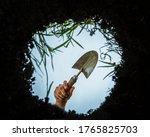 Small photo of View of a garden trowel or spade seen from inside the earth. Garden being weeded and dug up as seen from below the ground