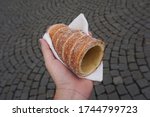 Hand holding a touristic trdelník spit cake in the streets of Prague, Czech Republic