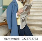 Small photo of St. Petersburg, Russia, September 21, 2022, Vitebsky railway station, depicts a girl in a yellow sweater, blue coat and jeans with a newspaper in her hands. Fake news, gossip, discredit